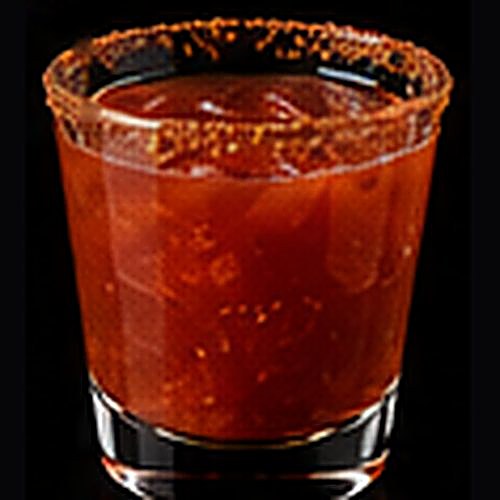 Michelada classic cocktail on a dark bar background